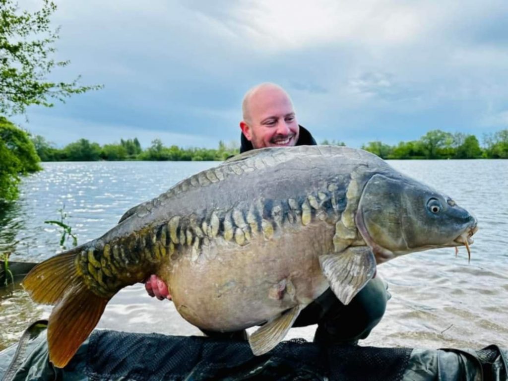 image d'un pêcheur avec une grosse carpe dans ses mains